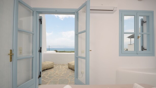 A room with a view of the sea, a bathtub, and a window with a mirror. - Depis Bay Apartments (Naxos)