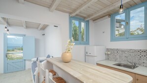 A modern kitchen with a wooden island, blue-framed windows, and a view of the outdoors. - Depis Bay Apartments (Naxos)