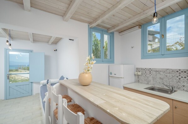 Una cocina moderna con una isla de madera, ventanas con marcos azules y vistas al exterior.