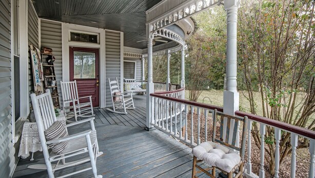 A covered porch with white railings and a wooden deck. - Clyde and Marie's Bed & Breakfast (Forest)