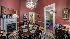 A dining room with a fireplace, chandelier, and a dining table set for six. - Clyde and Marie's Bed & Breakfast (Forest)