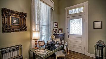 A room with a vintage typewriter, a radiator, a wooden floor, and a door with stained glass.