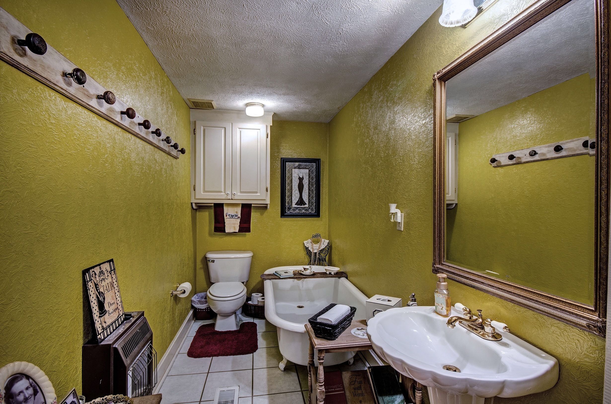 A bathroom with a white bathtub, a white sink, and a toilet. There is a mirror on the wall and a shelf with various items.