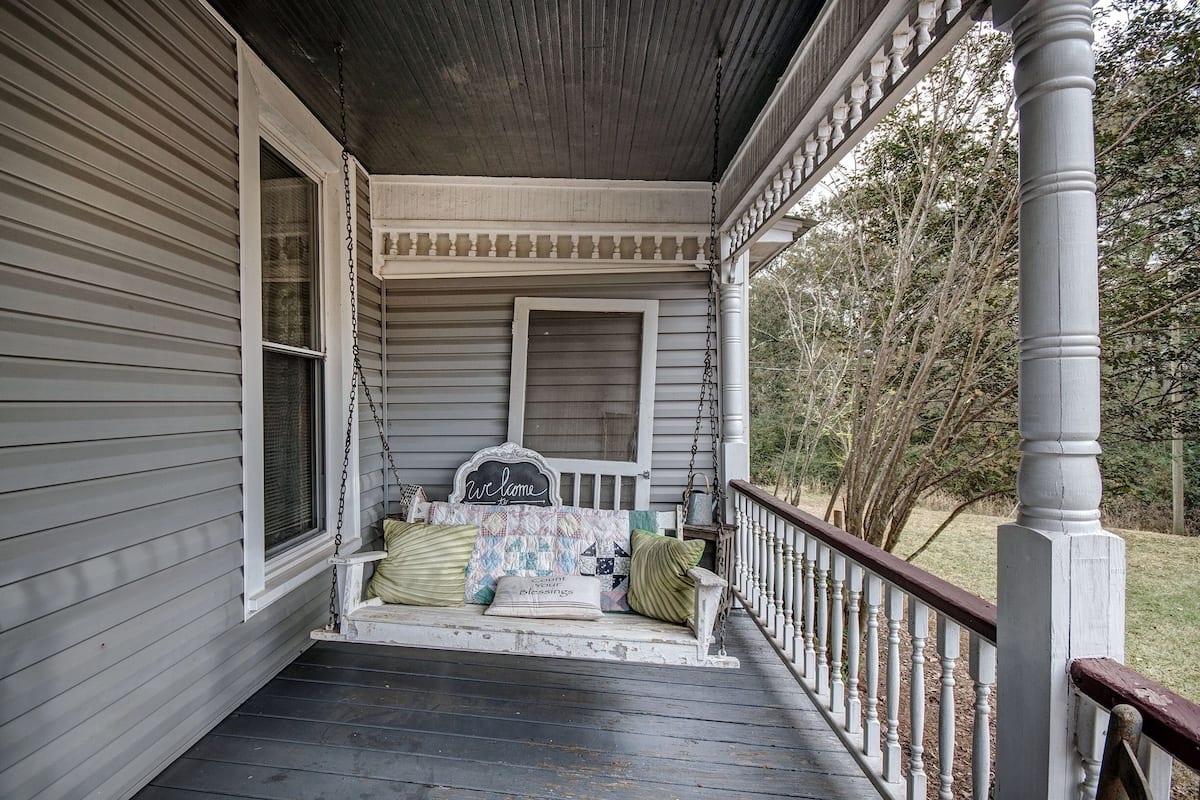 A porch with a bench, a welcome sign, and a view of the surrounding trees.