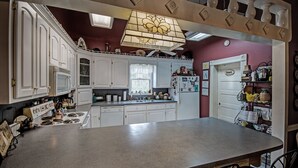 A kitchen with white cabinets, a granite countertop, a stove, and a ceiling fan. - Clyde and Marie's Bed & Breakfast (Forest)