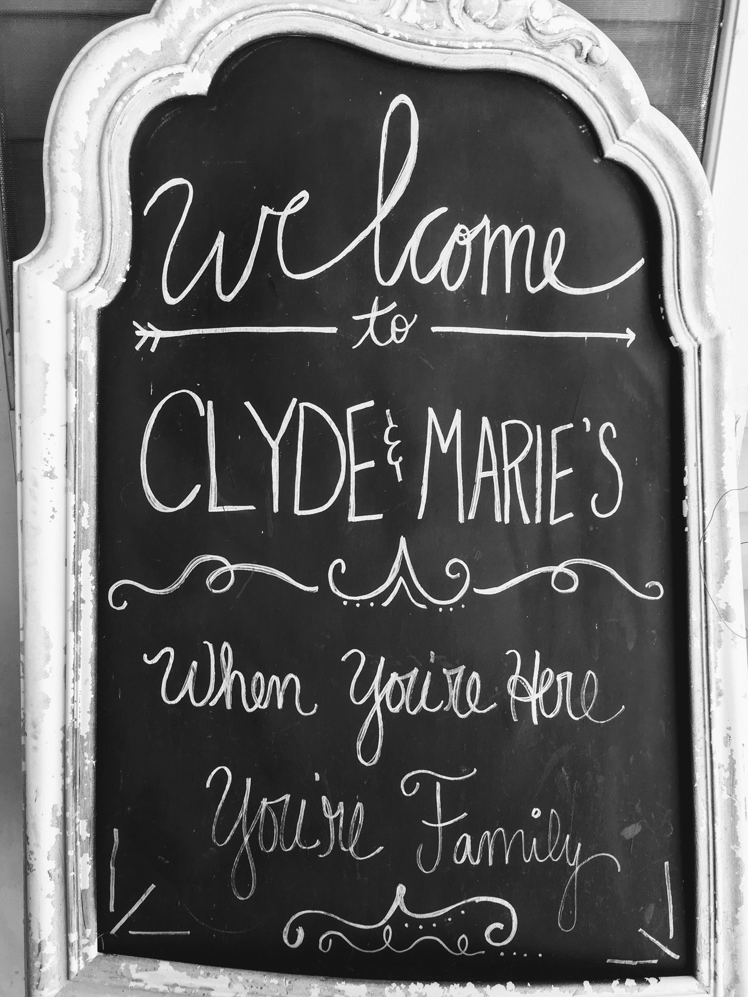 A blackboard with white chalk writing that reads "Welcome to Clyde & Marie's when you're here, you're family."