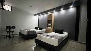 A modern hotel room with two beds, a wooden wardrobe, a desk, and a chair. - Hotel Laureles de Aburra Medellin (Medellín)
