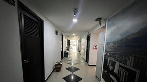 A hotel hallway with black and white checkered flooring, doors on both sides, and a mural of a cityscape on the right wall. - Hotel Laureles de Aburra Medellin (Medellín)