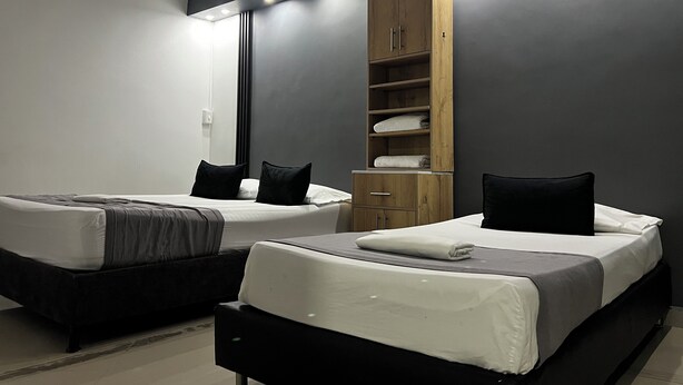A modern hotel room with two beds, a wooden wardrobe, and a large mirror. - Hotel Laureles de Aburra Medellin (Medellín)