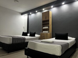 A modern hotel room with two beds, a wooden wardrobe, and a large mirror. - Hotel Laureles de Aburra Medellin (Medellín)