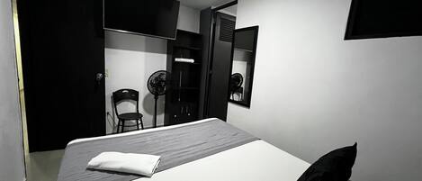 Une chambre d’hôtel moderne, dotée d’un grand lit, d’une chaise, d’un bureau et d’une armoire.