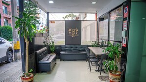 A reception area with a sofa, chairs, a small table, and potted plants. - Hotel Laureles de Aburra Medellin (Medellín)