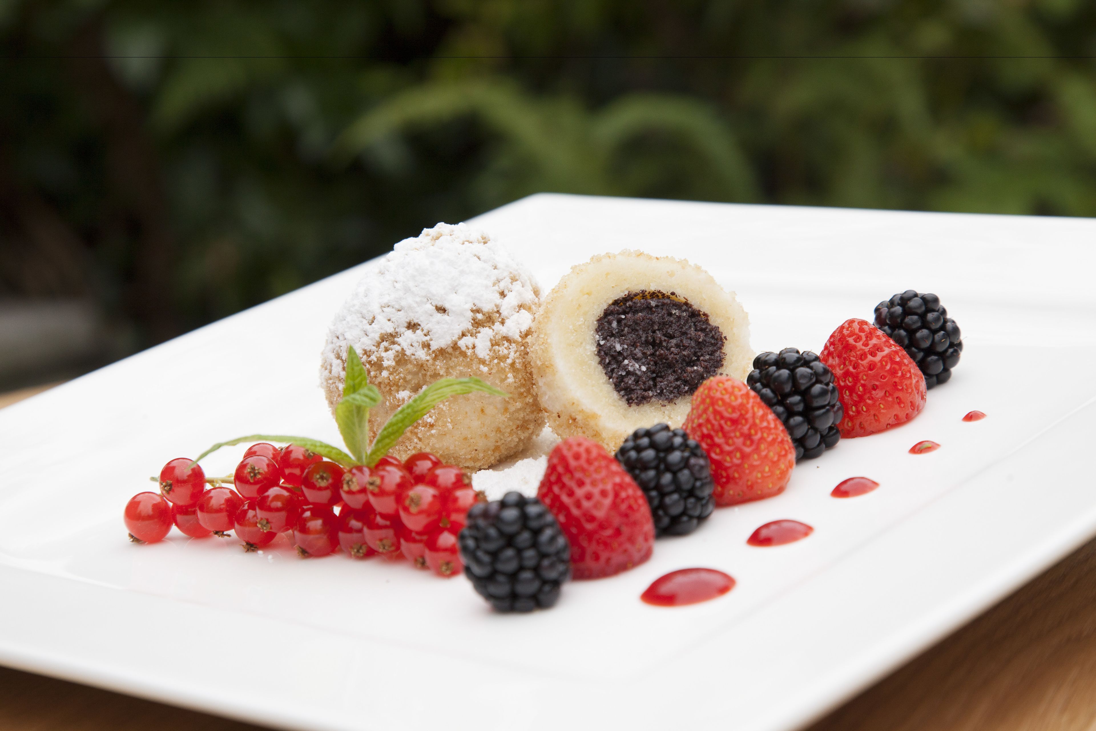 Une assiette à dessert avec une pâtisserie ronde saupoudrée de sucre glace, un centre garni de fruits rouges et un assortiment de baies et de groseilles rouges.