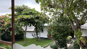 Um jardim com um deck de madeira, uma parede branca e um caminho que leva a um edifício.