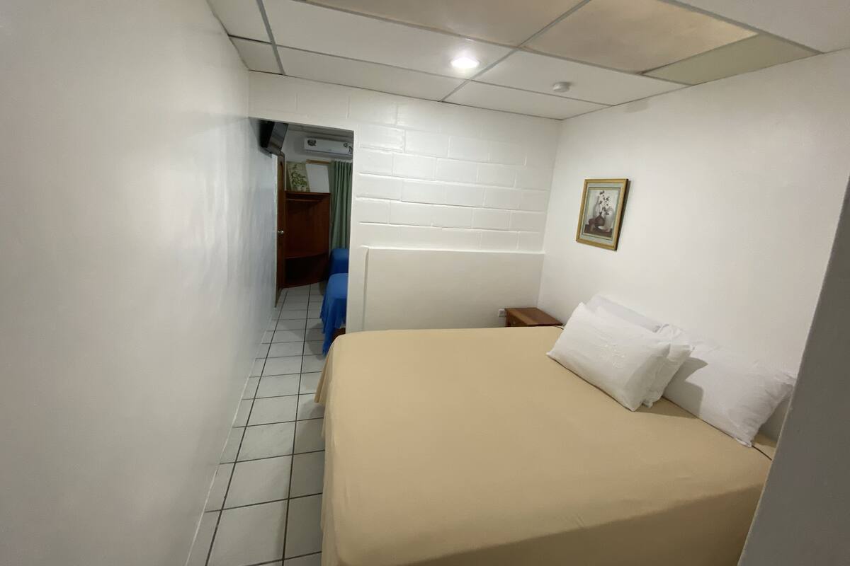 Een kleine, schone kamer met een enkel bed, een klein tafeltje en een kledingkast.