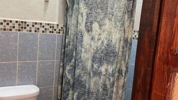 A bathroom with a toilet, shower curtain, and tiled walls.