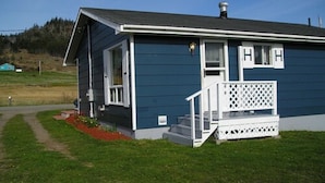 A single-story house with a porch, a visible chimney, and a small garden area. - Gullivers Cove Oceanview Cottages (Gullivers Cove)