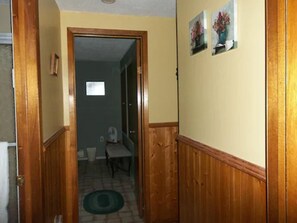 A hallway with wooden paneling, a dining area with a table and chairs, and a small window in the background. - Gullivers Cove Oceanview Cottages (Gullivers Cove)