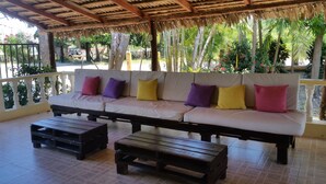Un espacio de estar al aire libre cubierto con un sofá y dos mesas de madera.