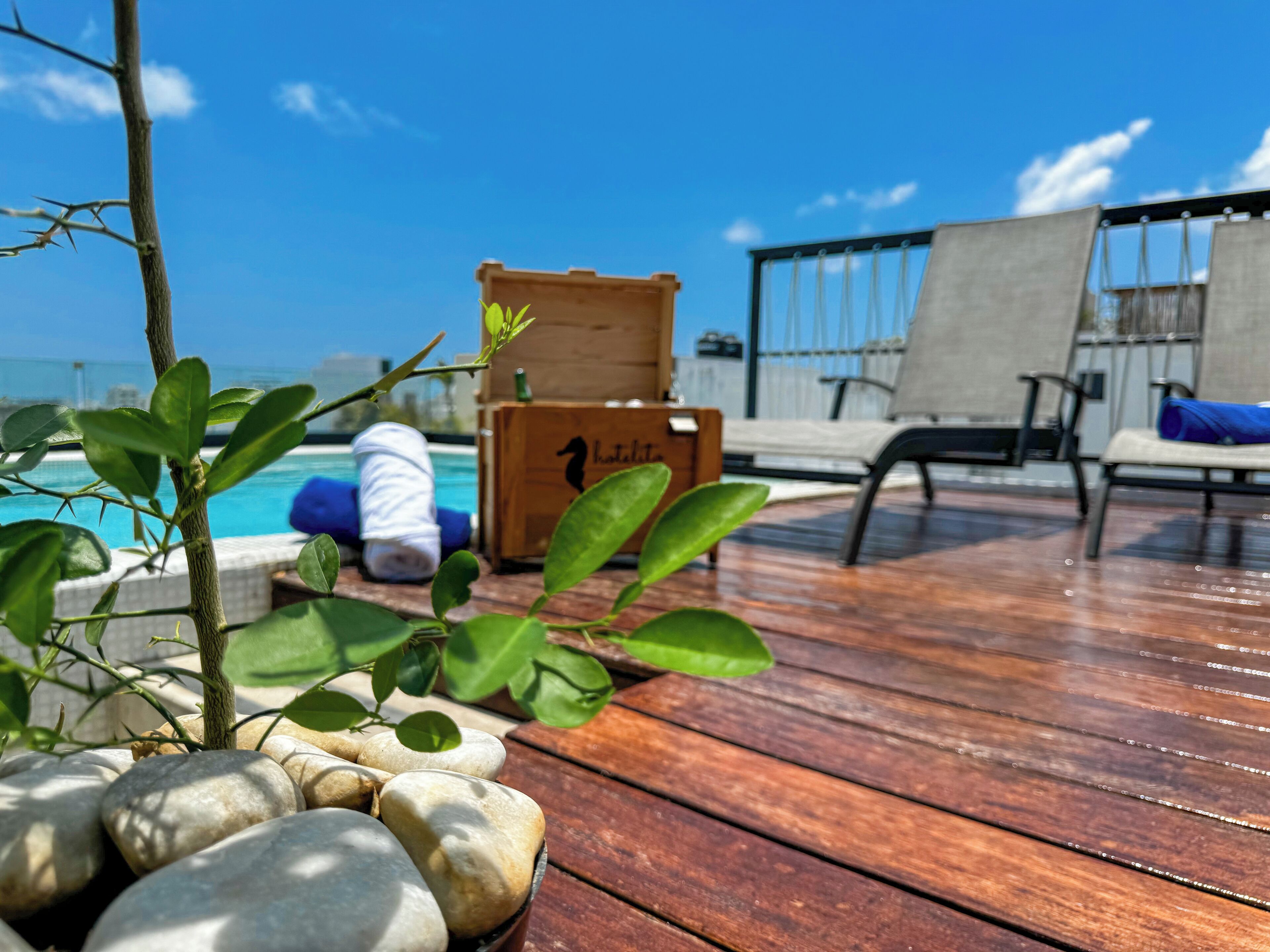 Een houten terras met loungebedden, een zwembad en een houten kist met de tekst 'hotel'.