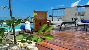 Een houten terras met loungebedden, een zwembad en een houten kist met de tekst 'hotel'.