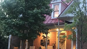 A brick building with a porch, a sign reading "The His House Inn," and an American flag. - Historic Iron Horse Inn (Hermann)