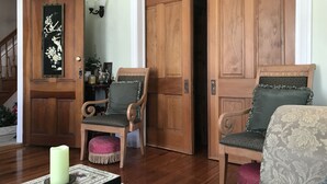 A wooden-floored living room with two wooden chairs, a table with a candle, and a door leading to another room. - Historic Iron Horse Inn (Hermann)