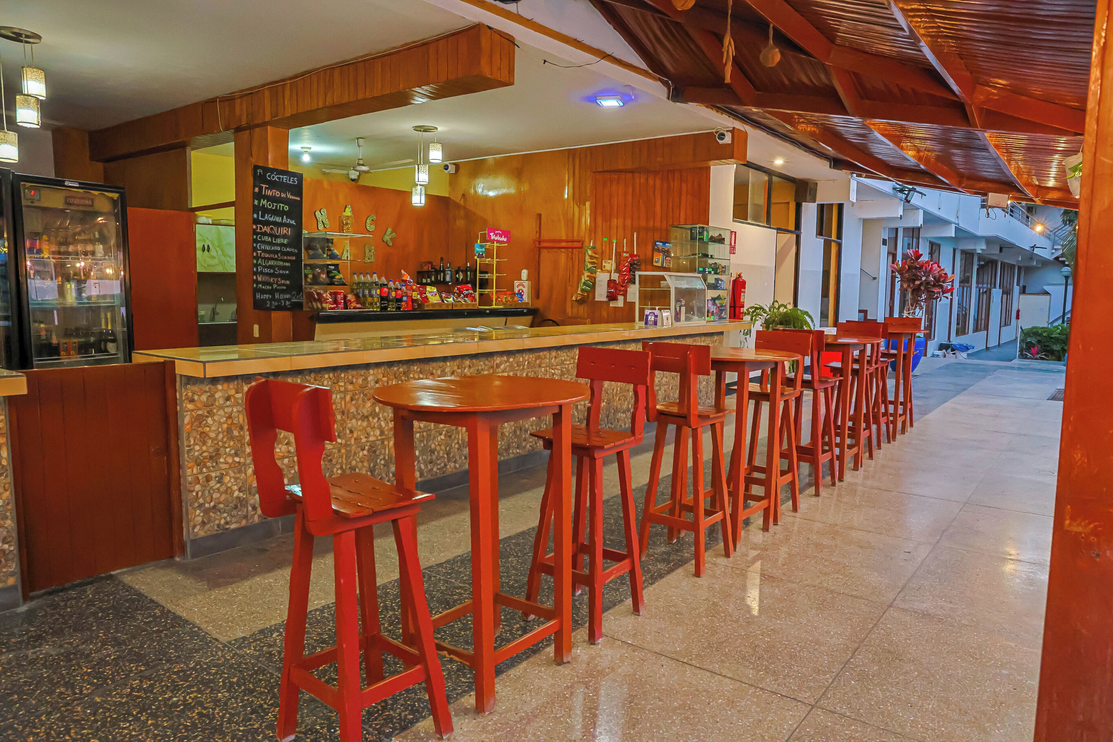 A bar area with a counter, red chairs, and a menu board.