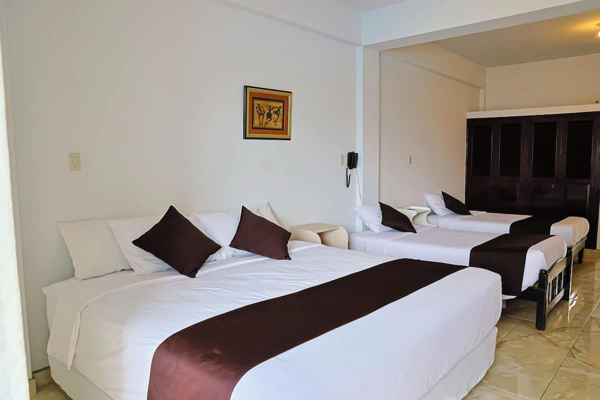 A hotel room with two beds, a bedside table, a telephone, and a framed picture on the wall.