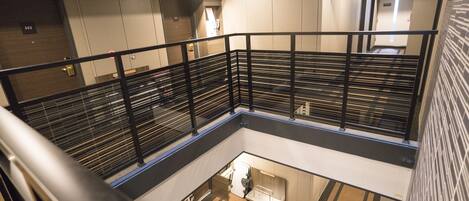 A hotel interior with a modern design, featuring a central atrium, a staircase, and a fire extinguisher near the entrance.