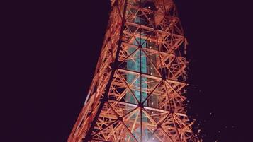 Ein nächtlicher Blick auf den Eiffelturm mit seiner filigranen Eisenstruktur und beleuchteten Bereichen.