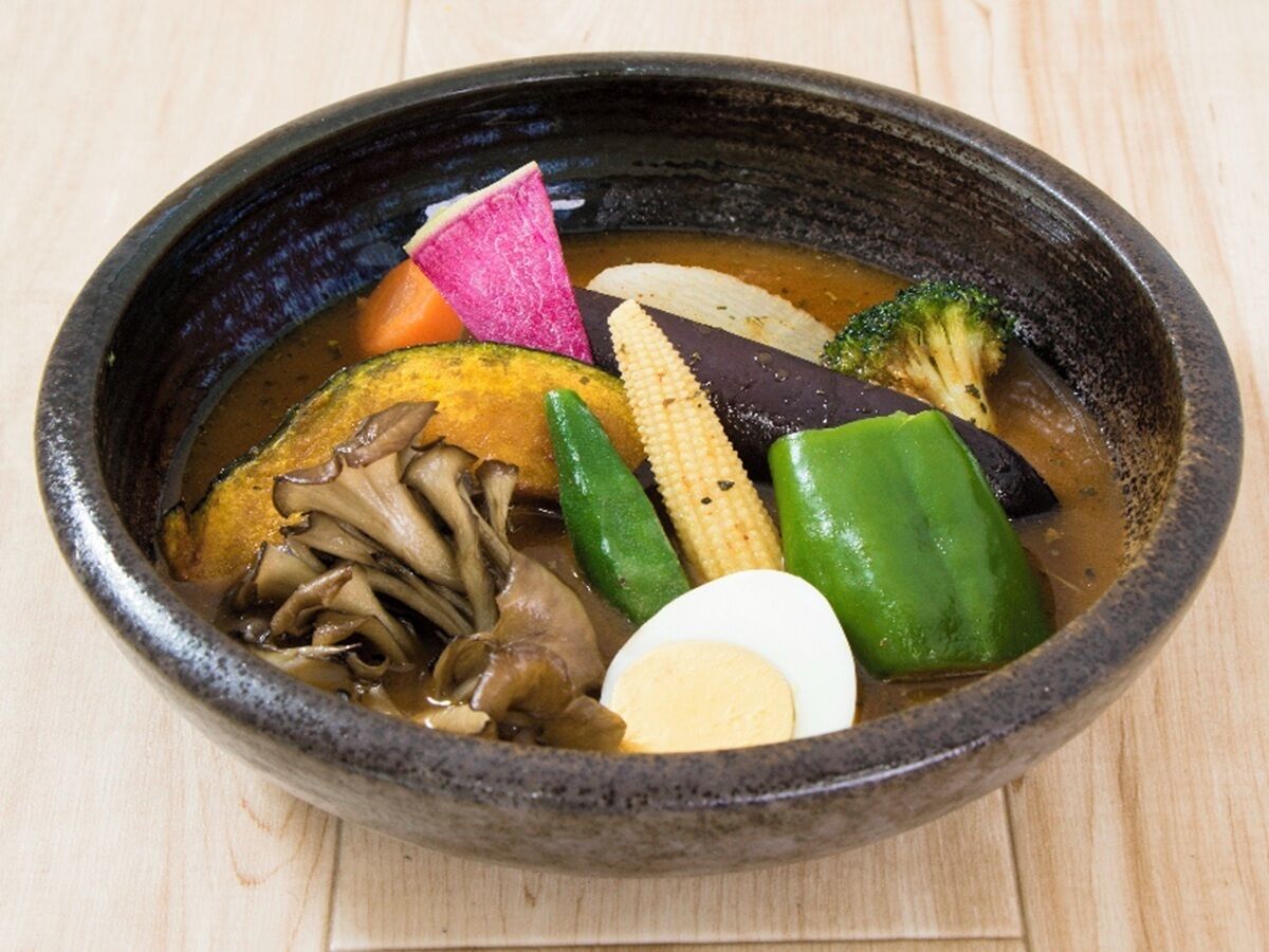 A bowl of soup with various vegetables and a boiled egg.
