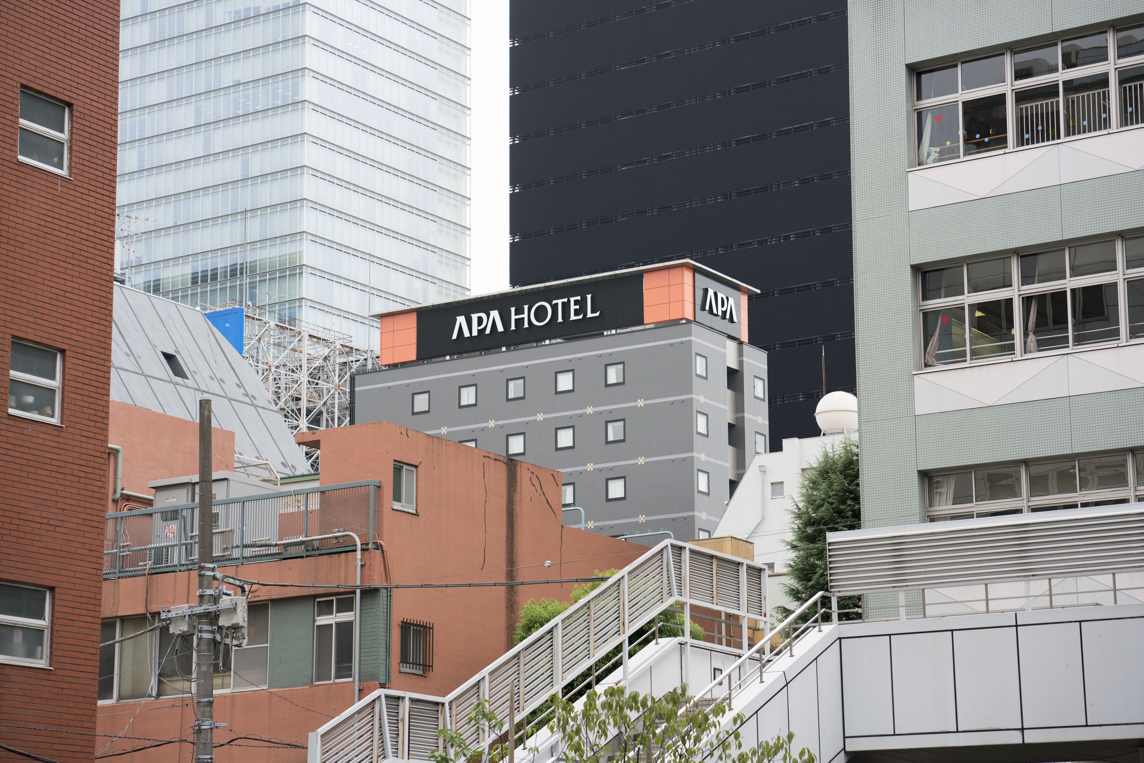 A multi-story building with the sign "APA HOTEL" on the top.