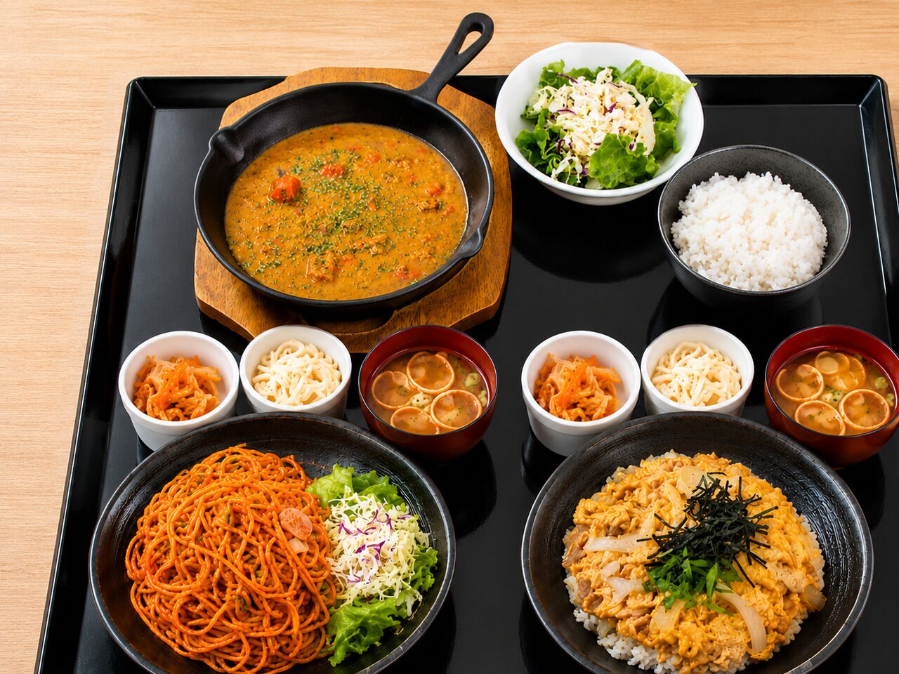 Un plateau contenant divers plats japonais, notamment des nouilles, du riz et de la soupe.