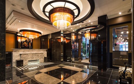 A lobby with a marble floor, a reception desk, and a large chandelier.