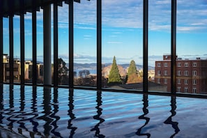 A room with a large window, a reflective floor, and a view of buildings and trees. - ibis Styles Hobart (Hobart)