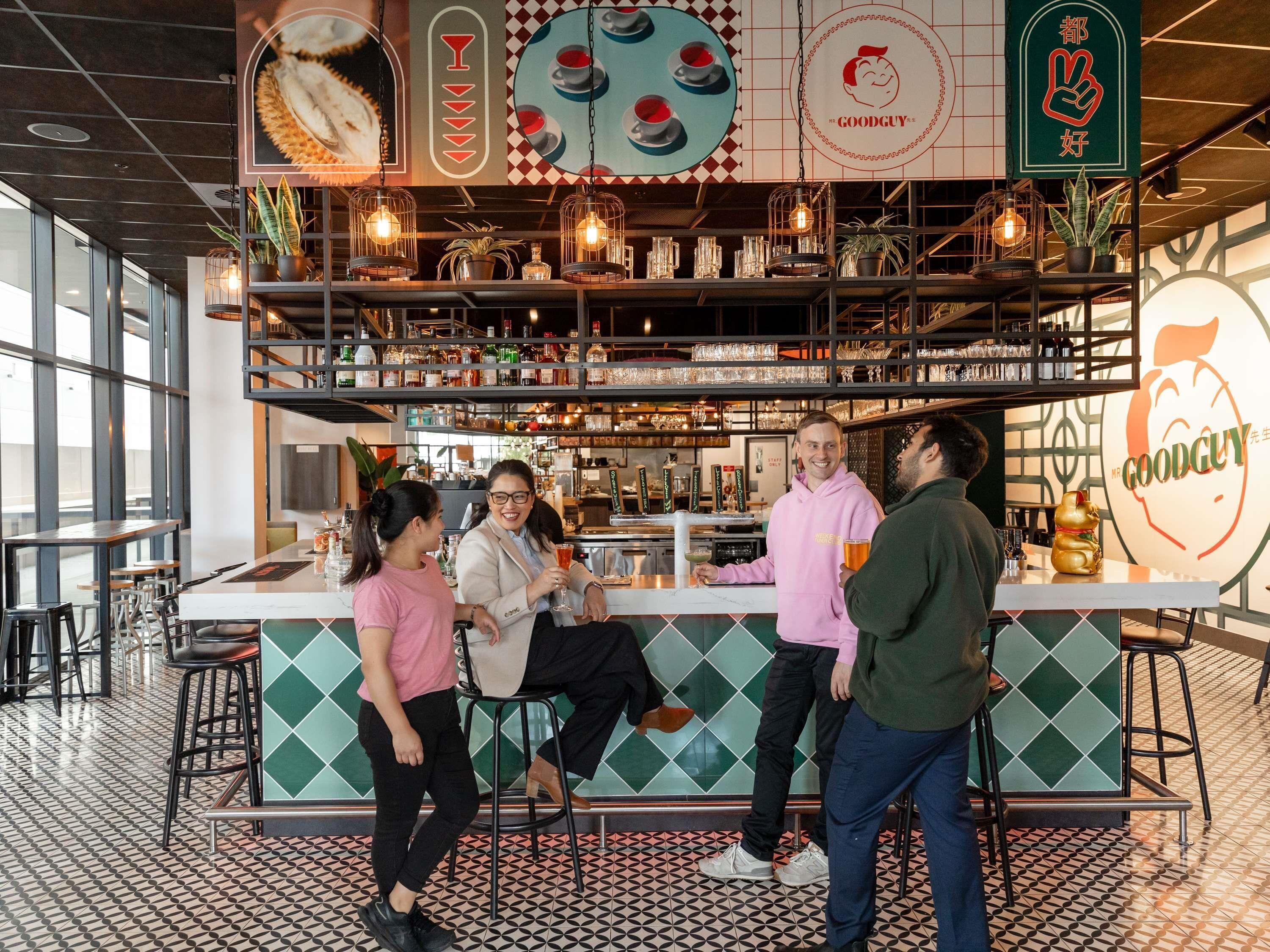 Angolo bar con bancone, sgabelli e scaffali pieni di bottiglie.