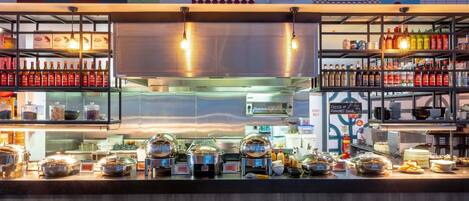 Un buffet avec différents plats présentés dans des récipients et accompagné de condiments variés.