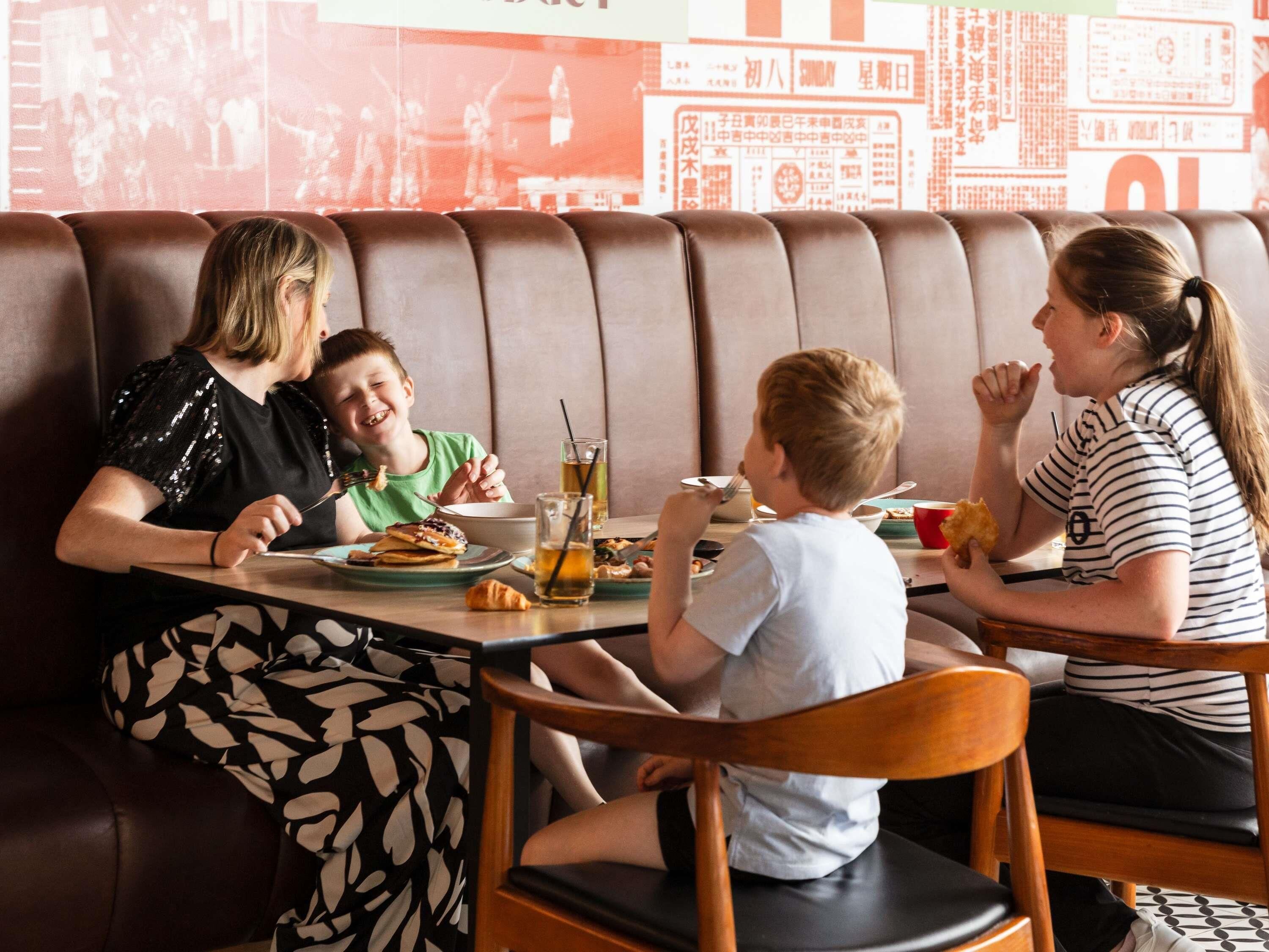 A group of people dining at a booth with a high backrest and cushioned seating.