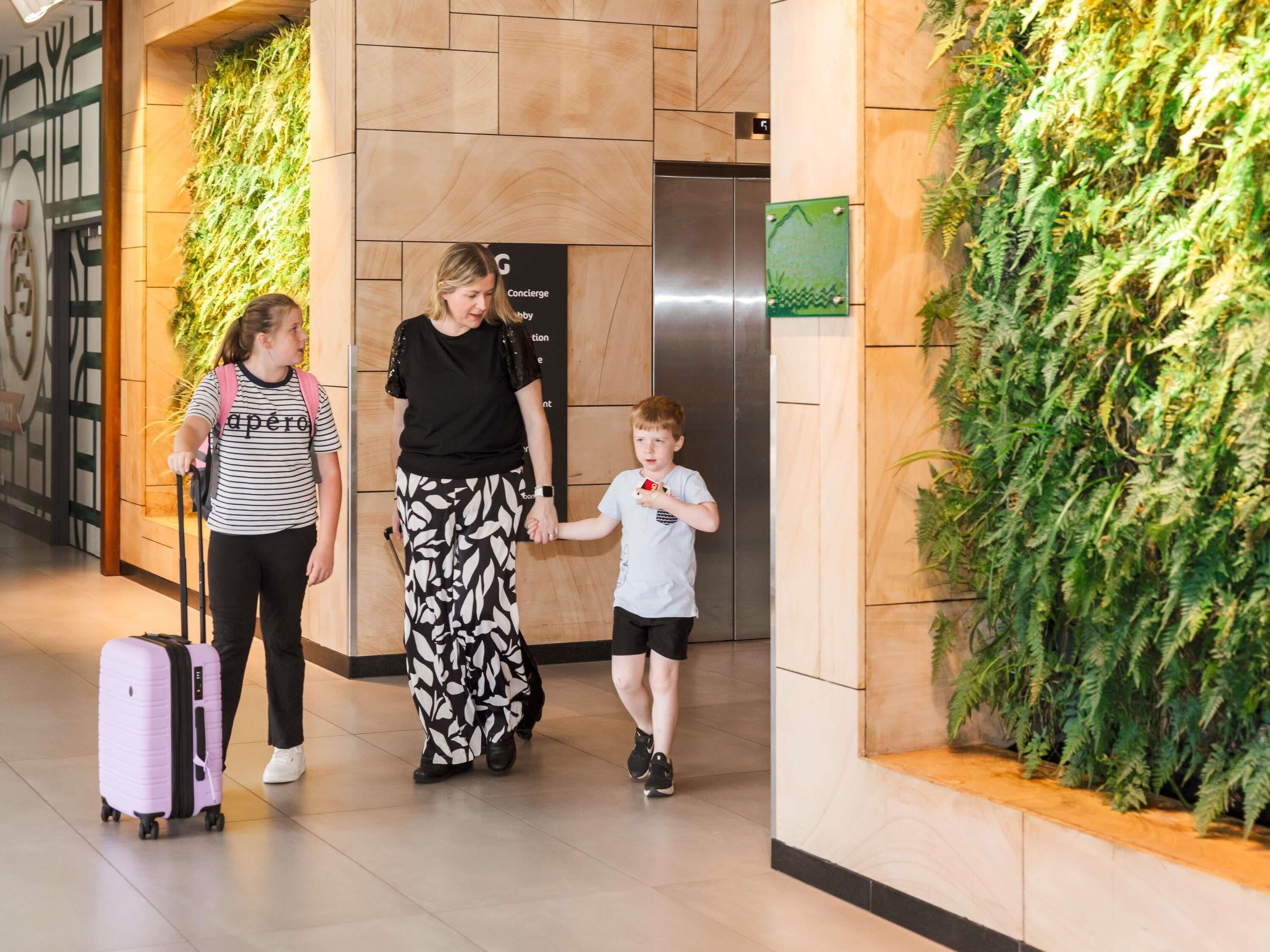 A lobby with a modern design, including a wall with vertical greenery, a sign for a concierge service, and a visible elevator.