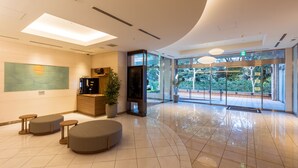 A modern lobby with a reception desk, seating area, and large glass doors leading to an outdoor space. - JR-East Hotel Mets Mejiro (Tokyo)