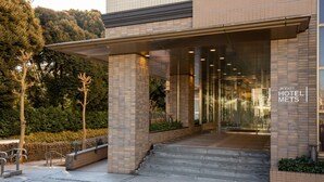 The entrance to JR-East Hotel Mets with a modern design, featuring a glass facade and a brick exterior. - JR-East Hotel Mets Mejiro (Tokyo)