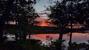 Una vista tranquila del lago, con abundante vegetación y un atardecer.
