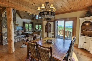 Enjoy meals in this dining area with a large table and six chairs, surrounded by a high ceiling and a decorative chandelier.