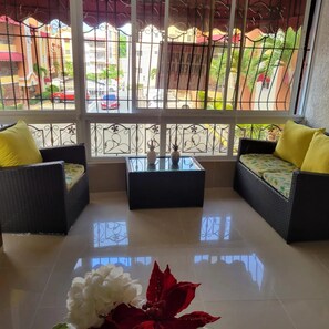 A room with two wicker sofas, a glass coffee table, and a potted plant.
