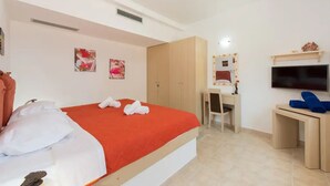 Ein Hotelzimmer mit einem Bett, einem Schreibtisch, einem Stuhl, einem Fernseher und einem Kleiderschrank.