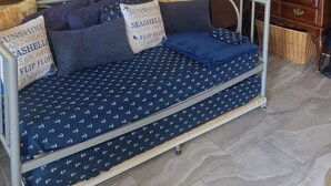 Une pièce comprenant un canapé-lit, un gouvernail de bateau fixé au mur, une carte encadrée et un meuble en bois.