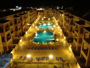 A hotel with a central swimming pool surrounded by lounge chairs and a poolside area. - Prime Location Ground Floor, 1 bed apartment. 2 Lagoon Pools, UK TV, FREE Wi-Fi (Paphos)