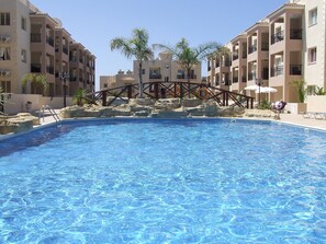 Una piscina al aire libre, sombrillas, tumbonas