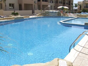 Una piscina al aire libre, sombrillas, tumbonas